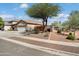 View of the house exterior showcasing the desert landscaping, three car garage, and mature shade tree at 16876 W Stevenage St, Surprise, AZ 85374