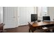 Bright home office with wood desk, dual monitors, and three white closet doors at 16876 W Stevenage St, Surprise, AZ 85374