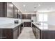 Bright kitchen showcasing stainless steel appliances, dark cabinets, granite countertops, and wood-look tile flooring at 18007 W Camino De Oro --, Surprise, AZ 85387