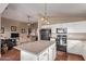 Bright eat-in kitchen featuring white cabinetry, island, and black appliances adjacent to the cozy living room at 1806 N 108Th Ave, Avondale, AZ 85392