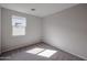A light and airy bedroom with neutral carpet, a window, and light gray walls at 18171 W Daley Ln, Surprise, AZ 85387