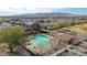 Aerial view of a community pool, covered seating and tennis courts, against a mountain backdrop at 18171 W Daley Ln, Surprise, AZ 85387