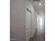 Bright hallway with neutral walls and wood-look tile flooring leading to a room with sliding glass doors at 18171 W Daley Ln, Surprise, AZ 85387