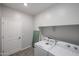 A tidy laundry room features modern washer and dryer, with a convenient shelf, and a paneled door for easy access at 18171 W Daley Ln, Surprise, AZ 85387