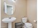 Charming half-bathroom featuring a pedestal sink, a round mirror, toilet, and neutral color walls at 18601 N 16Th Pl, Phoenix, AZ 85024