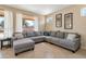 Comfortable living room featuring a large gray sectional sofa, tiled floors, and natural light from multiple windows at 18601 N 16Th Pl, Phoenix, AZ 85024