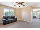 A spacious loft area with large windows, a ceiling fan, carpeting, and comfortable black leather sofa at 18601 N 16Th Pl, Phoenix, AZ 85024