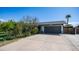 Charming single-story home featuring a gray two-car garage, mature trees, and a concrete driveway at 18829 N 23Rd Ave, Phoenix, AZ 85027