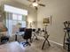 Bright home office featuring a glass desk, ceiling fan, and a large window offering natural light at 26521 N 114Th Pl, Scottsdale, AZ 85255