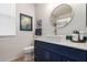 Chic bathroom featuring a navy blue vanity, modern round mirror, and contemporary fixtures, with artful decor at 27315 N 83Rd Dr, Peoria, AZ 85383
