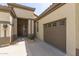 Tan home with a wooden door, a brown garage door, and the house number displayed at 27315 N 83Rd Dr, Peoria, AZ 85383