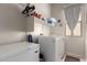 Efficient laundry room with ample storage, including a washer, dryer, and freezer, with natural light from a window at 27315 N 83Rd Dr, Peoria, AZ 85383