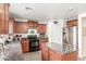 Traditional kitchen with granite countertops, wood cabinets, black appliances, and stainless refrigerator at 28071 N Superior Rd, San Tan Valley, AZ 85143