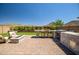 Entertainer's backyard with an outdoor kitchen, fire pit, and seating under the blue sky at 33275 N 132Nd Ave, Peoria, AZ 85383
