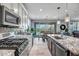 Modern kitchen with stainless appliances, granite counters, large island and bar seating open to the dining area at 33275 N 132Nd Ave, Peoria, AZ 85383