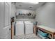 Functional laundry room with a washer, dryer, storage shelves, and a patterned tile floor at 33275 N 132Nd Ave, Peoria, AZ 85383