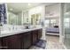 Bathroom featuring double sinks with dark wood cabinets, a large mirror, and open view to bedroom at 3855 S Mcqueen Rd # 24, Chandler, AZ 85286