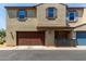 Charming two-story townhome featuring a brown two car garage and neutral-colored stucco exterior at 3855 S Mcqueen Rd # 24, Chandler, AZ 85286