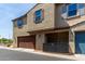 Two-story townhome featuring a brown two car garage and neutral-colored stucco exterior at 3855 S Mcqueen Rd # 24, Chandler, AZ 85286