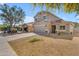 View of the home's facade, spacious driveway, desert landscaping, and mature tree at 4559 E Sierrita Rd, San Tan Valley, AZ 85143