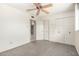 Bright bedroom featuring gray carpet, a ceiling fan, and closet with white doors at 5203 W Acoma Dr, Glendale, AZ 85306