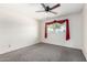 Bright bedroom with a ceiling fan, carpet, and large window dressed with red curtains at 5203 W Acoma Dr, Glendale, AZ 85306