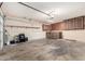 A large garage with unfinished floor, storage cabinets, and good lighting at 5203 W Acoma Dr, Glendale, AZ 85306