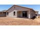 Rear view of the home with stucco exterior, covered patio, and yard with dirt ground cover at 7417 E Hackamore Ln, San Tan Valley, AZ 85143