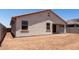 Rear view of the home showing stucco exterior, covered patio, and yard with dirt ground cover at 7417 E Hackamore Ln, San Tan Valley, AZ 85143