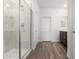 Modern bathroom features a glass-enclosed shower with marble-look surround and wood-look tile flooring at 7417 E Hackamore Ln, San Tan Valley, AZ 85143