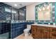 Stylish bathroom features blue tiling, walk-in shower, and wood vanity with marble counter at 7678 E Cactus Wren Rd, Scottsdale, AZ 85250