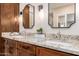 Bathroom featuring double sinks, granite countertops, and wood cabinets at 7678 E Cactus Wren Rd, Scottsdale, AZ 85250