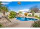 Private backyard pool with waterfall feature, surrounded by lush landscaping and lounge chairs at 7678 E Cactus Wren Rd, Scottsdale, AZ 85250