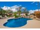 Sparkling pool with rock waterfall and lush landscaping, including a patio lounge area at 7678 E Cactus Wren Rd, Scottsdale, AZ 85250