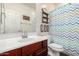 Bright bathroom features a wooden vanity, patterned shower curtain and wooden shelves at 12057 W Ashby Dr, Peoria, AZ 85383