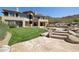 Backyard with a stone patio, grass lawn, desert landscaping, pool, and luxurious home exterior at 12639 N 136Th St, Scottsdale, AZ 85259