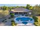 Aerial view of an inviting backyard featuring a sparkling pool, spa, lounging area, mature trees and mountain views at 14022 W Hope Dr, Surprise, AZ 85379
