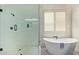 Luxurious bathroom features a glass shower and soaking tub with shuttered window and tile flooring at 14022 W Hope Dr, Surprise, AZ 85379