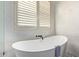 Elegant bathroom featuring a freestanding tub with black fixtures and a window with shutters at 14022 W Hope Dr, Surprise, AZ 85379