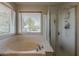 Bright bathroom featuring soaking tub and walk-in shower with glass door at 14874 W Laurel Ln, Surprise, AZ 85379