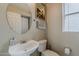 Powder room with pedestal sink, round mirror, and neutral wall color at 14874 W Laurel Ln, Surprise, AZ 85379