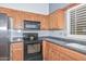 Close-up of the kitchen with wood cabinets, granite countertops and black oven at 15035 W Indianola Ave, Goodyear, AZ 85395