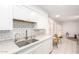 Kitchen features white cabinets, granite countertops, subway tile backsplash, and stainless steel sink at 17627 N 104Th Ave, Sun City, AZ 85373