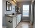 Bright bathroom featuring a double sink vanity, wood-look floors, and natural light from a large window at 1876 N Parkside Ln, Casa Grande, AZ 85122