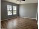 Bright bedroom with wood-look floors, a ceiling fan and two large windows providing ample natural light at 1876 N Parkside Ln, Casa Grande, AZ 85122