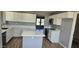 Modern kitchen features white cabinets, an island with a white countertop, and wood flooring at 1876 N Parkside Ln, Casa Grande, AZ 85122