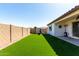 Large backyard area featuring artificial grass, storage, and a patio with lighting, and comfortable seating at 21056 W Granada Rd, Buckeye, AZ 85396