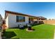 Fully turfed backyard with a small seating area and a covered patio for outdoor dining and relaxation at 21056 W Granada Rd, Buckeye, AZ 85396