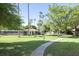 Beautifully maintained community grounds with lush green grass, mature trees, and walking paths at 2146 W Isabella Ave # 154, Mesa, AZ 85202