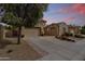 Beautiful exterior view of a desert home with a three-car garage, paver driveway, and manicured landscaping at dusk at 2664 E Ebony Dr, Chandler, AZ 85286